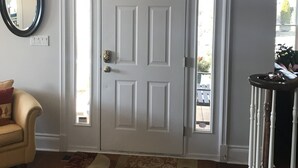 A room with a white door, a mirror, a patterned rug, and a light fixture. - Dicksons Family Suite B&B (Niagara-on-the-Lake)