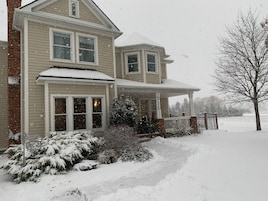 Una casa de dos pisos con un porche cubierto de nieve y un buzón.