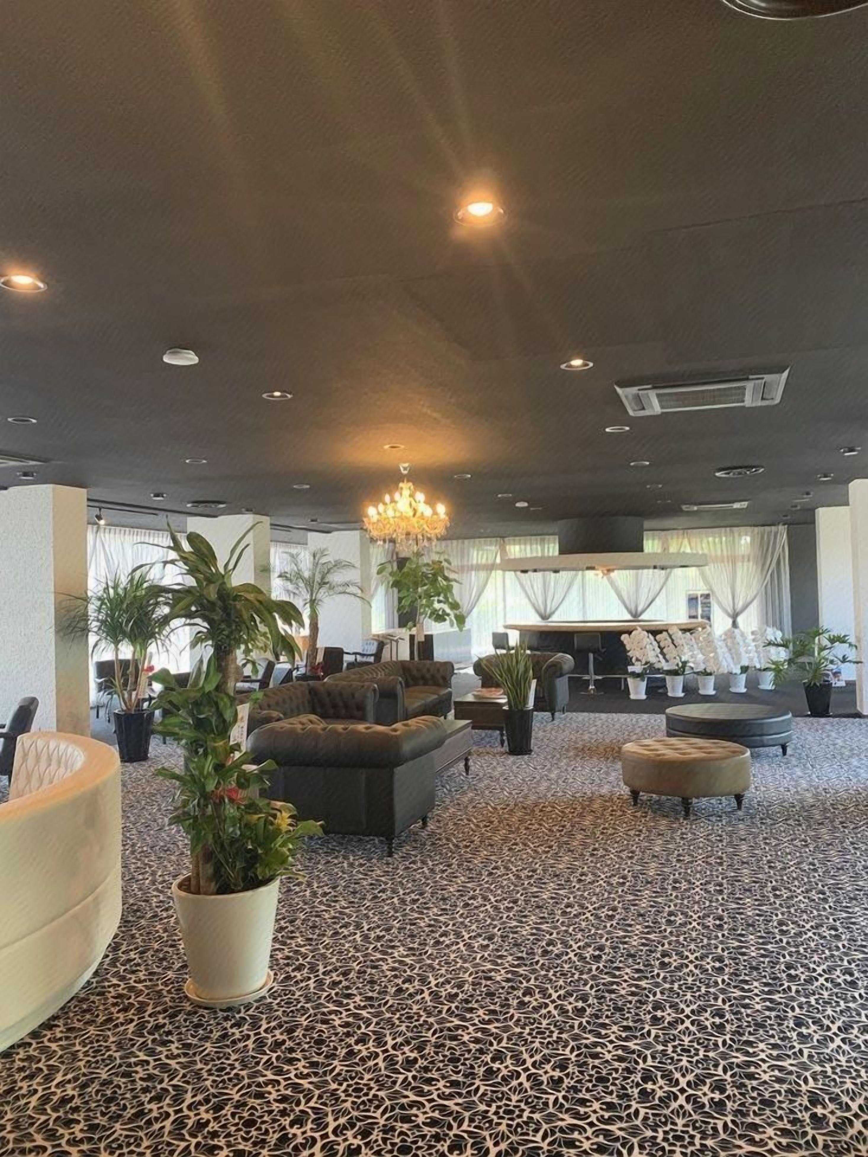 A spacious lobby with seating areas, a chandelier, and potted plants.