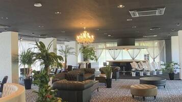 A spacious lobby with seating areas, a chandelier, and potted plants.
