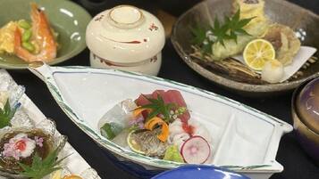 A variety of dishes on a table, including sushi, sashimi, and other Japanese cuisine.