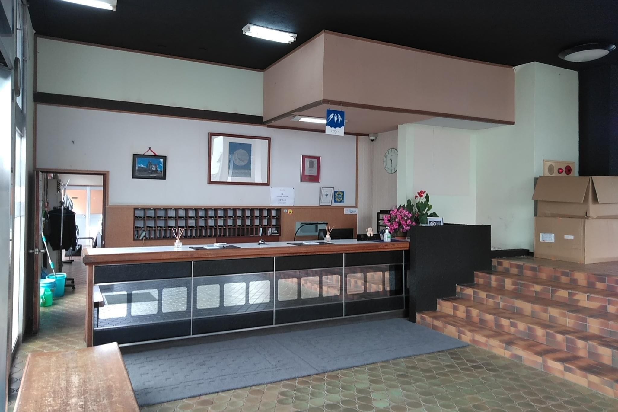 A reception desk with a counter, a clock, framed certificates, and a blue sign indicating a restroom.
