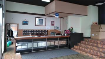 A reception desk with a counter, a clock, framed certificates, and a blue sign indicating a restroom.
