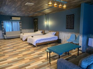 A hotel room with two beds, a blue table, and a blue chair. - Aoshima Suikoen Hotel (Miyazaki)