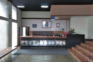 A reception desk with a counter, a clock, and framed certificates on the wall. - Aoshima Suikoen Hotel (Miyazaki)