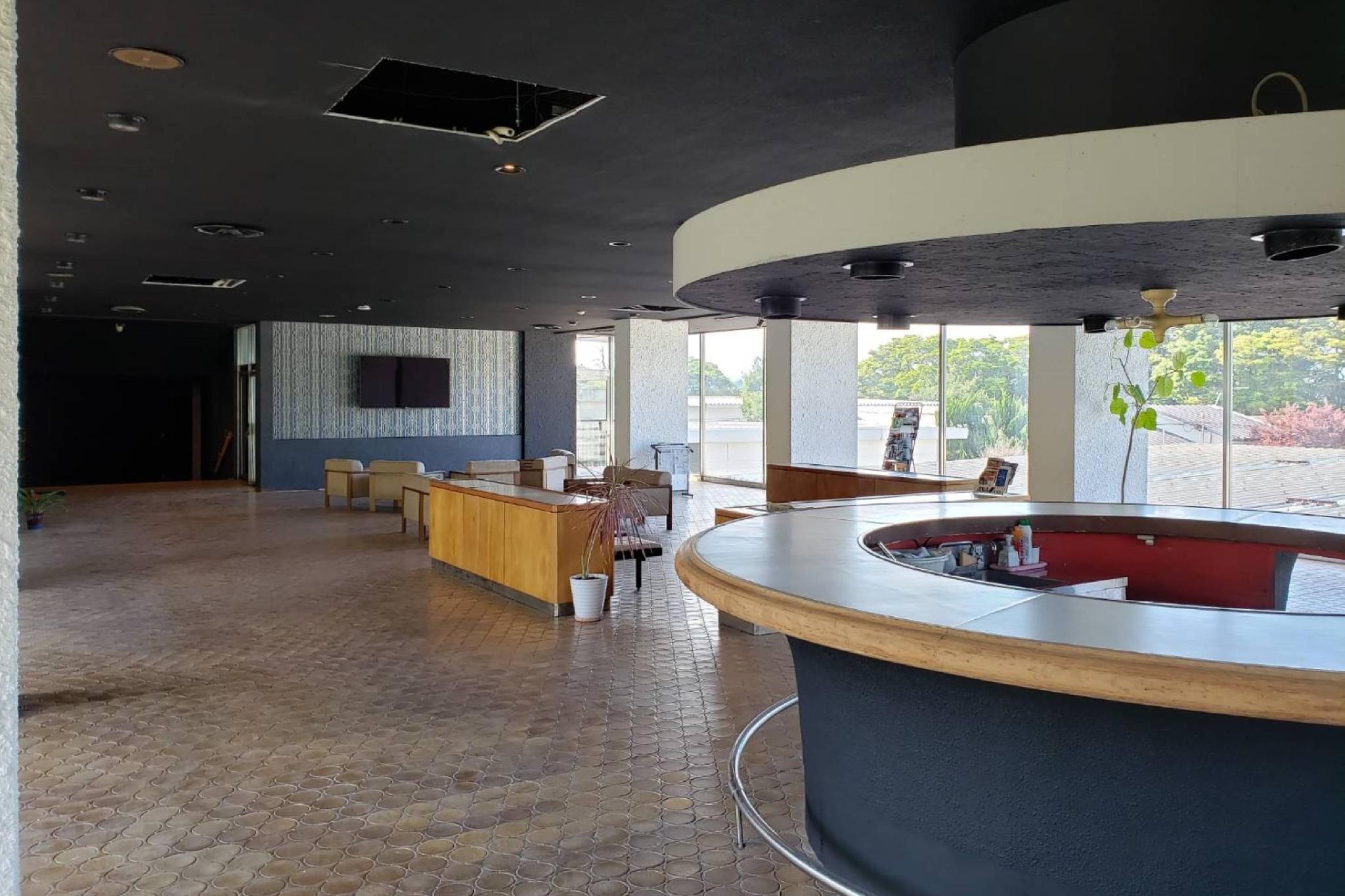 A spacious lobby with a reception desk, seating area, and large windows offering a view of the outdoors.