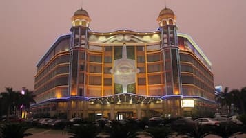 Um hotel com vários andares, um átrio central, várias varandas e uma entrada espaçosa.