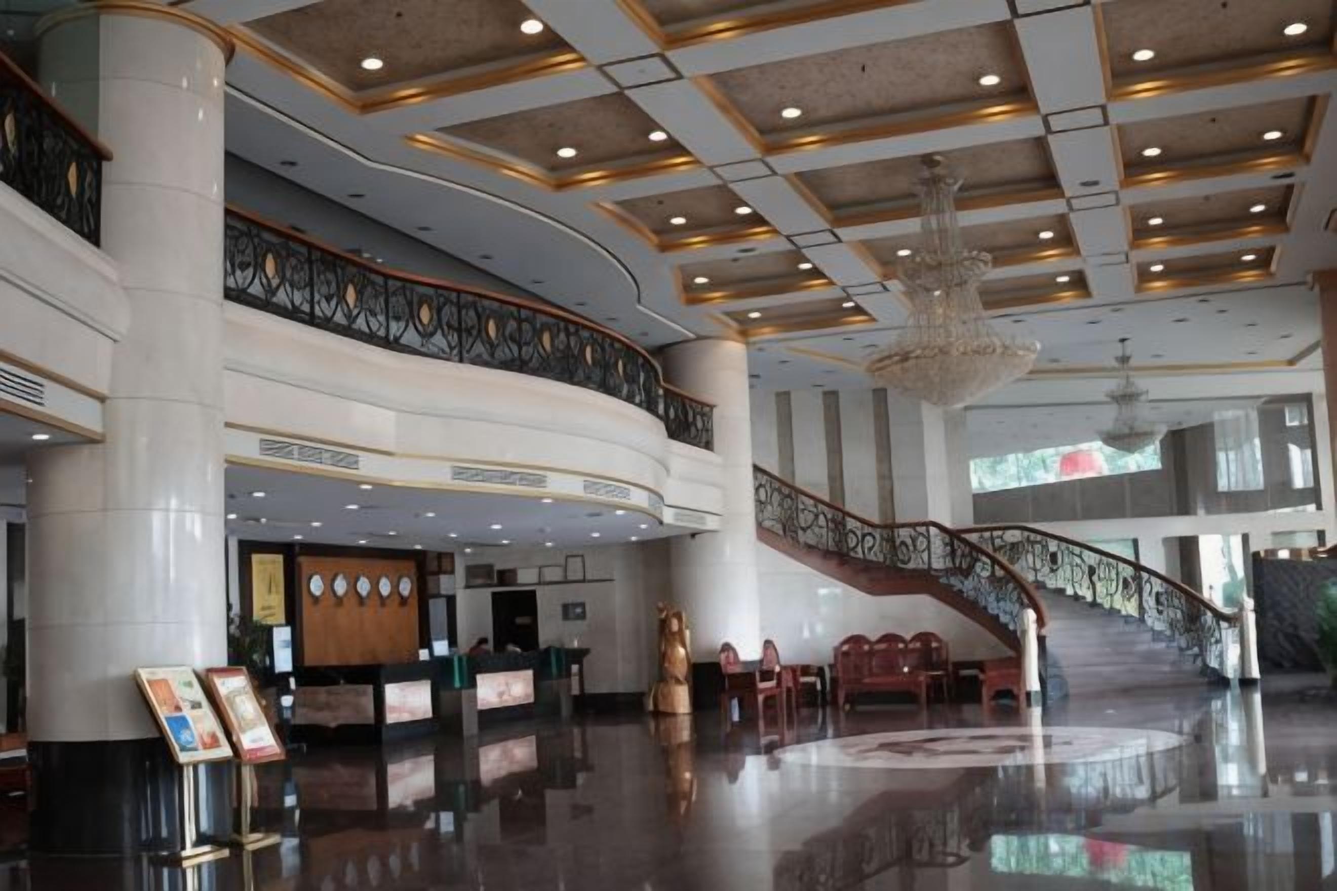 Un vestíbulo amplio con una recepción, una escalera y un candelabro.