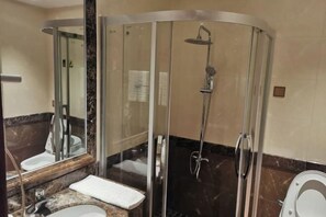 A modern bathroom with a glass-enclosed shower, a marble countertop, and a white sink. - The Dynast's Hotel (Foshan)