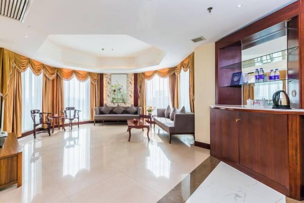 A spacious living area with a sofa, chairs, a coffee table, and a wooden cabinet with glass doors.