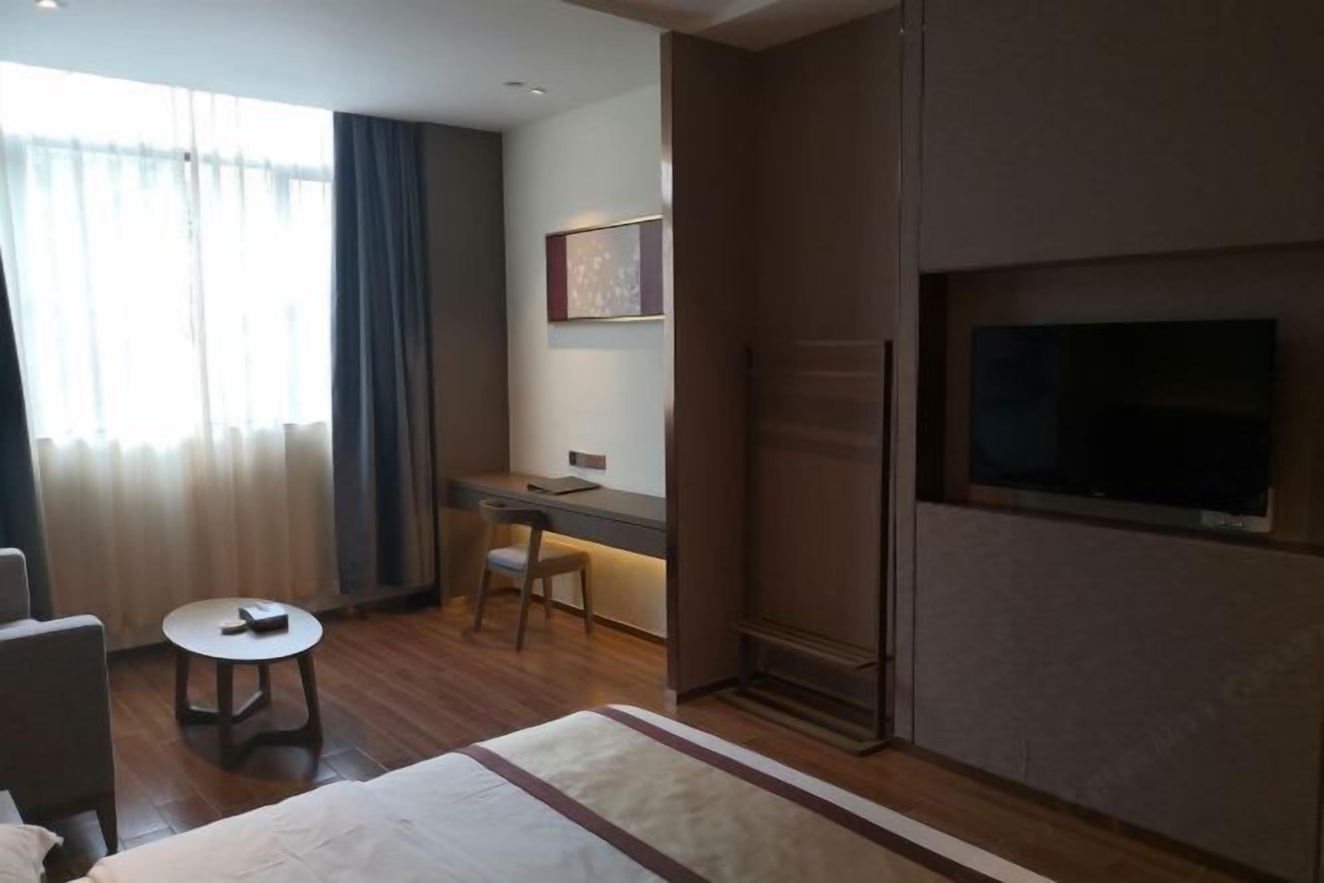 Une chambre d’hôtel équipée d’un lit, d’un bureau, d’une chaise, d’une télévision et d’une fenêtre avec des rideaux.