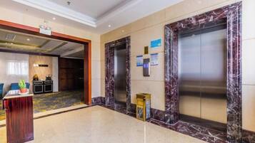 A lobby with marble flooring, an elevator, and a reception desk.