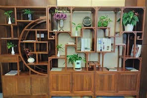 A wooden shelving unit with multiple compartments, some containing books and others with potted plants. - Long Teng International Hotel (Rucheng)