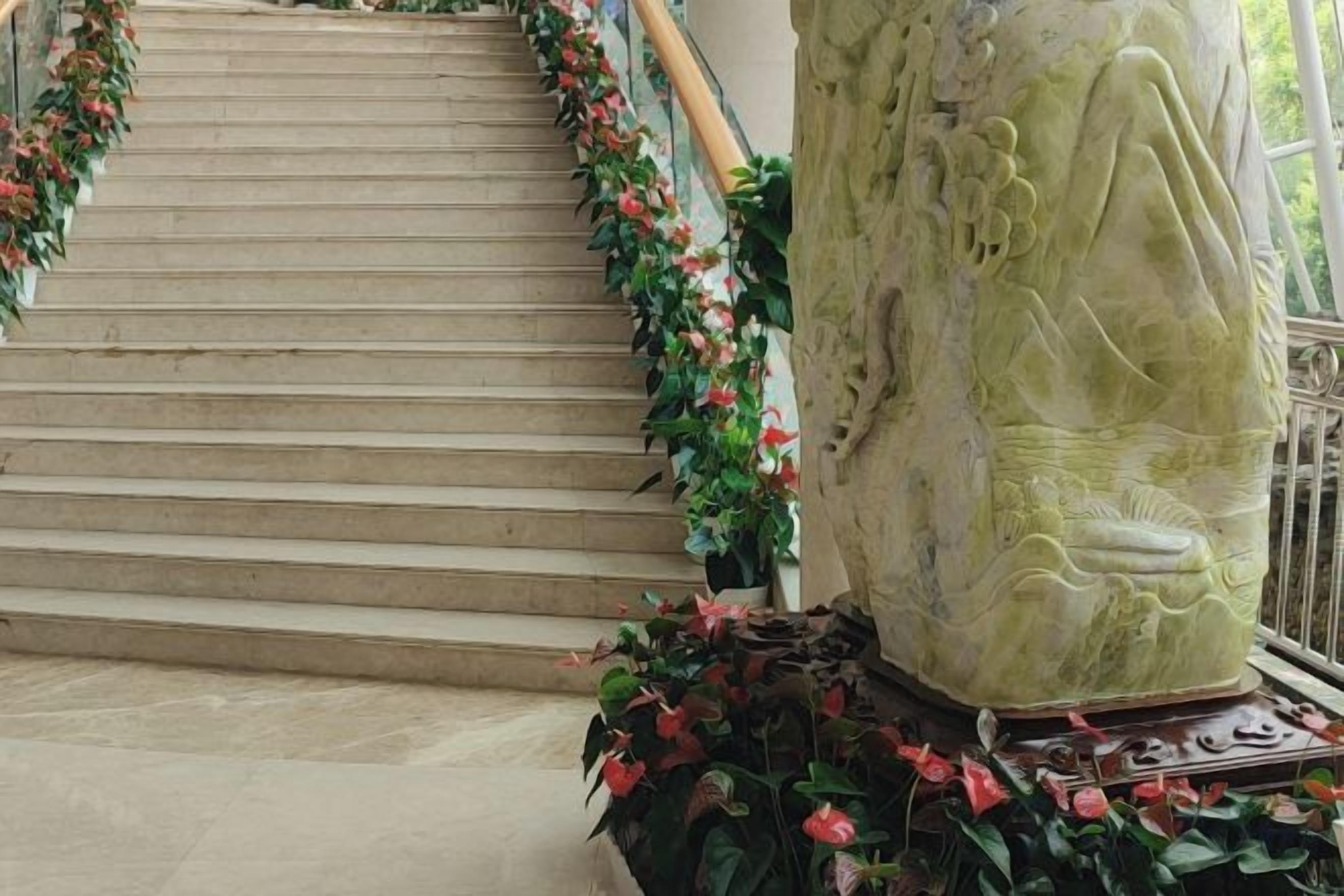 A staircase with a floral border, a stone column with carvings, and a railing.