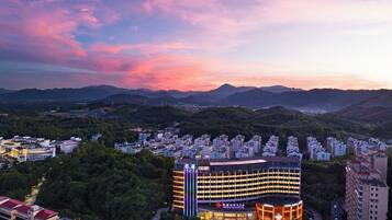 A hotel with a modern design, surrounded by a cityscape and mountains.