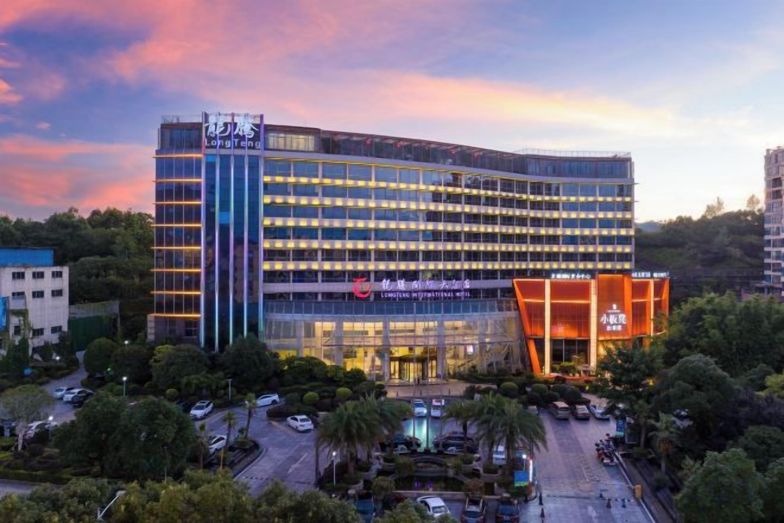 A multi-story hotel with a modern design, featuring a prominent entrance and a parking area.