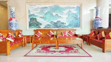 Un salón de estilo tradicional con muebles de madera, un cuadro grande y jarrones decorativos.