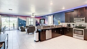 Una cucina moderna con mobili scuri, elettrodomestici in acciaio inossidabile e un murale a tema galassia.