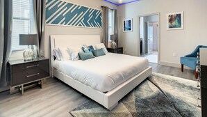 Una camera da letto moderna con un letto grande, un comodino, una cassettiera, un lampadario e una parete decorata.