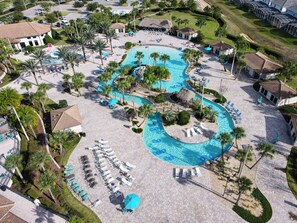 An aerial view of a resort with a large, winding pool, sun loungers, and palm trees. - Galactic Getaway - 8BR, Game Room, Pool & Theatre (Davenport)