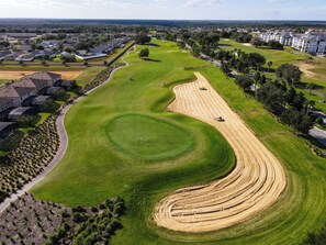 An aerial view of a golf course with a winding fairway, sand bunkers, and a clubhouse.