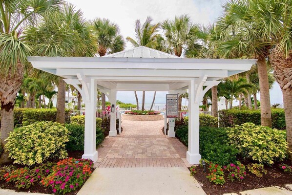 A covered walkway with a white gazebo, surrounded by palm trees and flowering plants. - Islamorada's Anglers Reef - Vaca in Style (Islamorada)