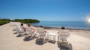 Una spiaggia con sedie bianche e una vista libera sull'oceano.