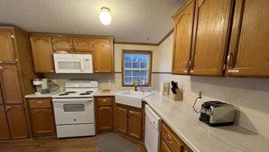 A kitchen with wooden cabinets, a white stove, a sink, and a toaster. - Life at the Dairy Farm (New Enterprise)