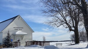 A white building labeled 'Featherstone Town Hall' with a snow-covered ground, a bench, and a tree in the background.