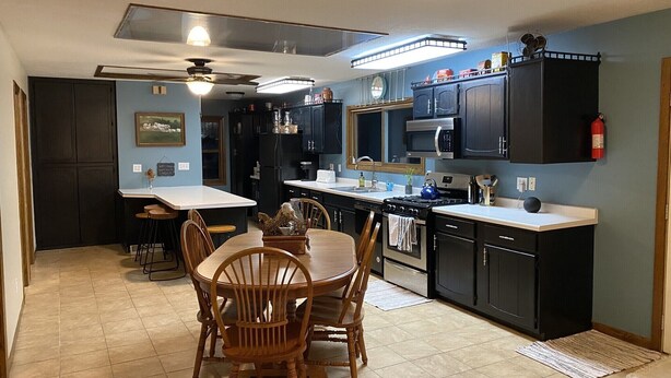 A kitchen with dark cabinets, a stove, microwave, and a dining area with wooden chairs and a table. - Spacious country home in a peaceful setting. New listing with frequent updates! (Red Wing)