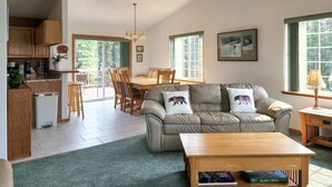 A spacious living room with a sofa, coffee table, and dining area. - Alaska Fly In / Drive In, Kenai Peninsula Lodging (Sterling)
