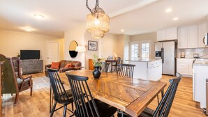 A spacious kitchen with modern appliances, a dining area with a wooden table and chairs, and a cozy living room with a fireplace. - Kid-Friendly 2 Bedroom close to Idaho Center & NNU (Nampa)