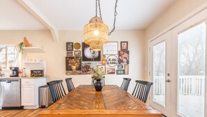 A dining area with a wooden table, black chairs, a hanging light fixture, and wall decorations. - Kid-Friendly 2 Bedroom close to Idaho Center & NNU (Nampa)