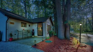 A cabin with a number 417 sign, a covered patio with outdoor seating, and a large tree to the right.