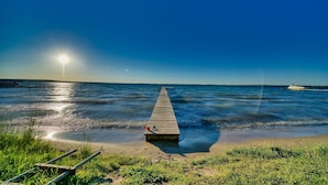 A wooden pier extending into calm waters with a clear sky.