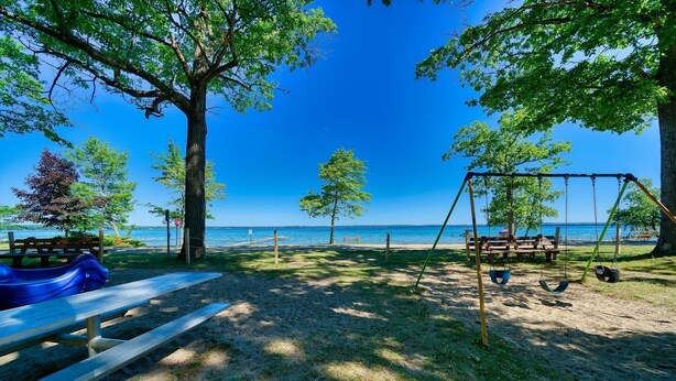 A beachside park with picnic tables, a swing set, and a view of the sea.