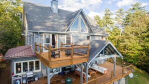 A large house with a wooden deck, a covered patio, and a chimney. - Jewel of the Woods - Magnificent Views from an Incredible Lodge! (Clayton)