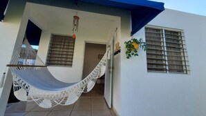 A building with a blue roof, a white wall, and a hammock hanging on the porch. - Comfy apartment 8 minute walk from beach (Aguadilla)