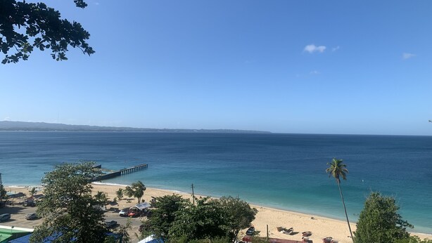 A beach with a pier extending into the water, surrounded by trees and buildings. - Comfy apartment 8 minute walk from beach (Aguadilla)