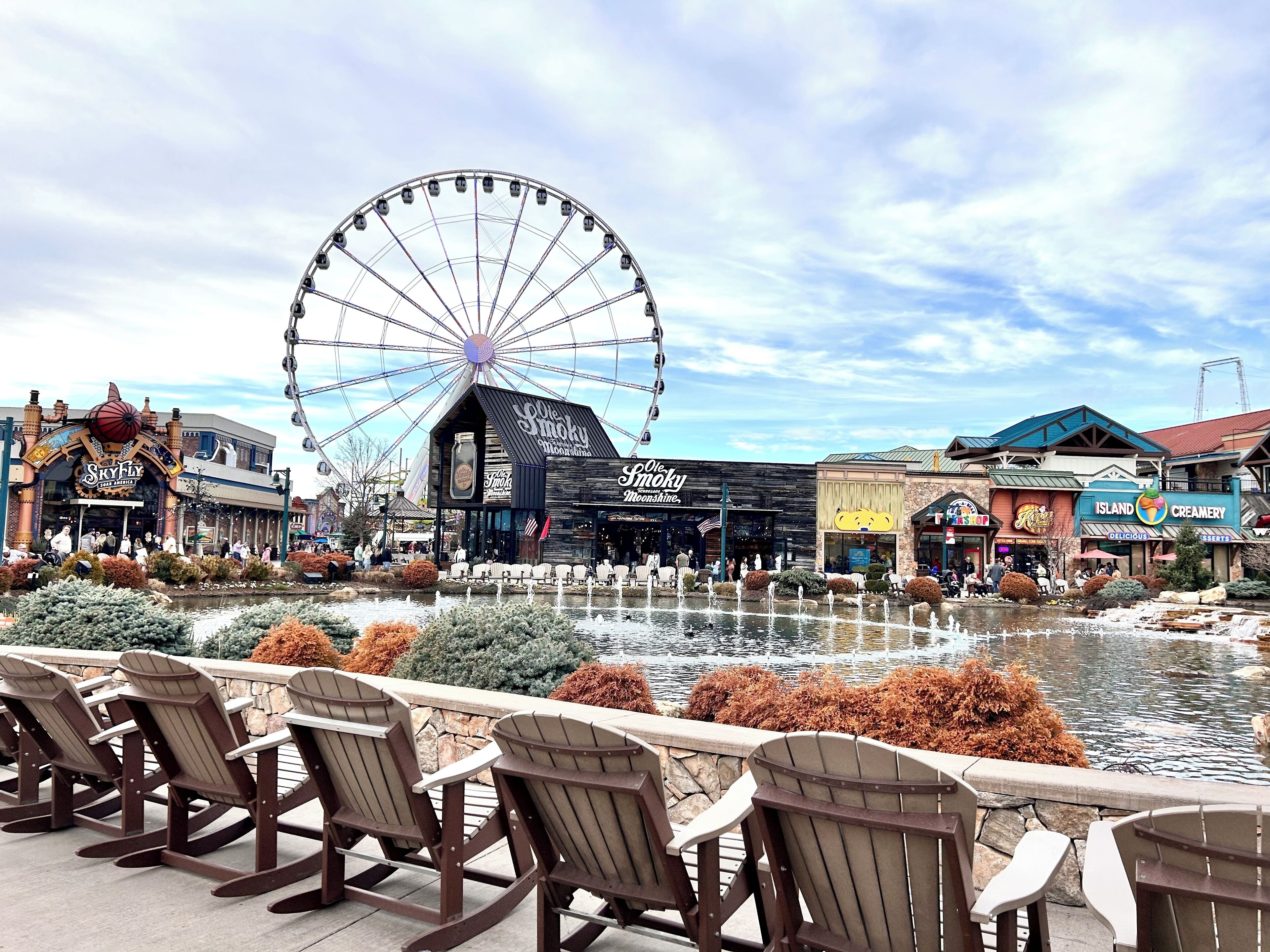A waterfront area with a Ferris wheel, outdoor seating, and various shops.