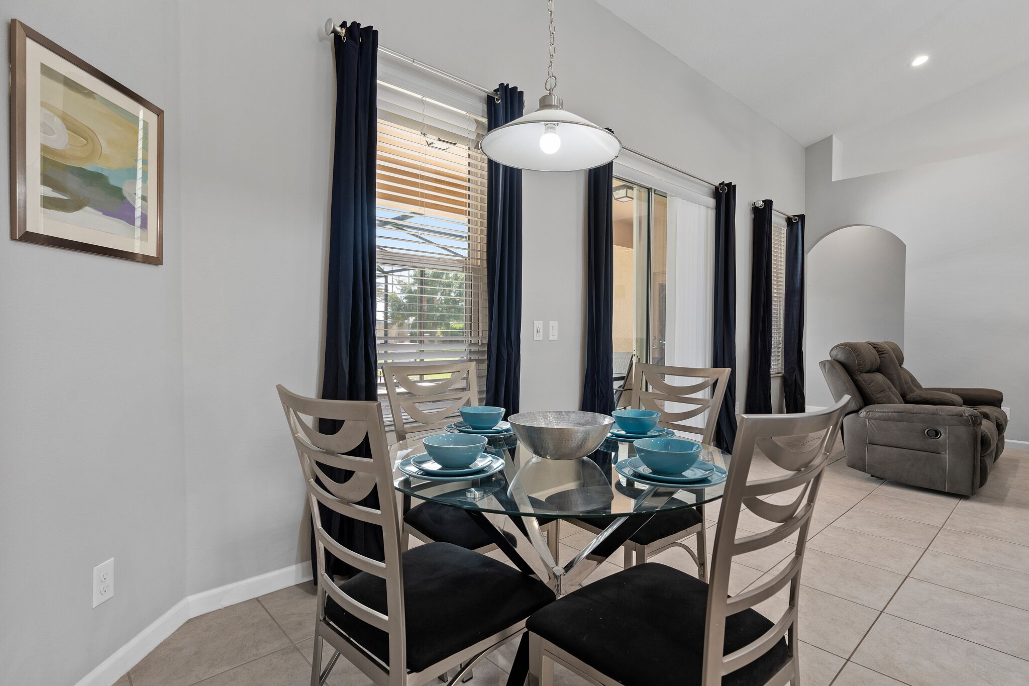 A dining area with a glass table, chairs, and blue bowls.