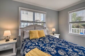 Een slaapkamer met een bed, twee nachtkastjes, een lamp en een raam met zonwering.