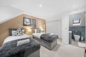 A modern bedroom with two beds, a skylight, and a bathroom with a shower and toilet. - Luxury House • Pool Table • Free Parking • Sky TV • Fast Wifi • Garden • Yoko Property (Milton Keynes)