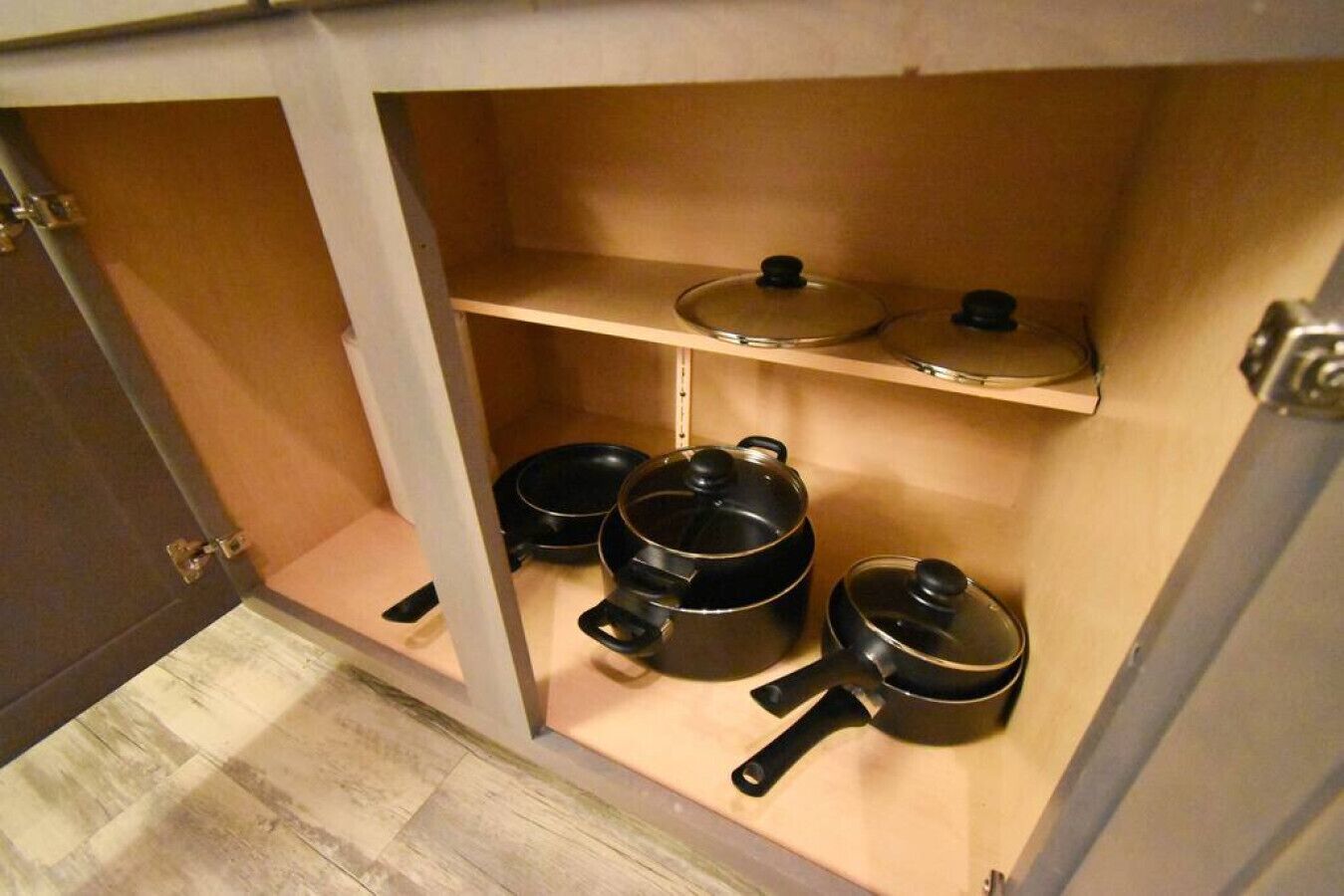 A kitchen with wooden shelves and black pots.