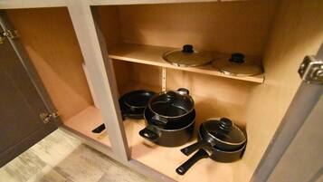 A kitchen with wooden shelves and black pots.