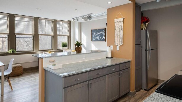 Una cocina moderna con encimera de granito, armarios empotrados y refrigerador de acero inoxidable.