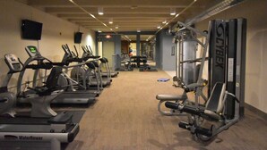 Un gimnasio con cintas de correr, una máquina de remo y poleas.