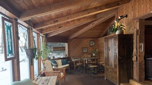 Een knus houten interieur met een eethoek, een tafel en stoelen, en een zithoek met comfortabele stoelen.