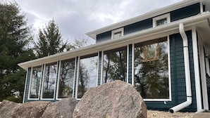 Een huis met grote ramen en een overdekte veranda.