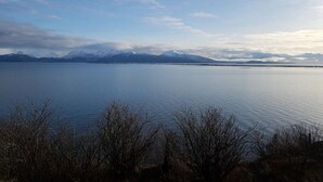 A calm lake with mountains in the background and sparse vegetation in the foreground. - Oceanfront Luxury Apartment Overlooking Kachemak Bay and Homer Spit! (Homer)